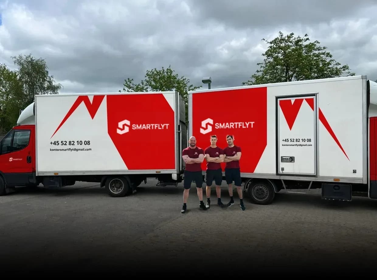 The Smart Flyt team in front of two moving vans with the company logo