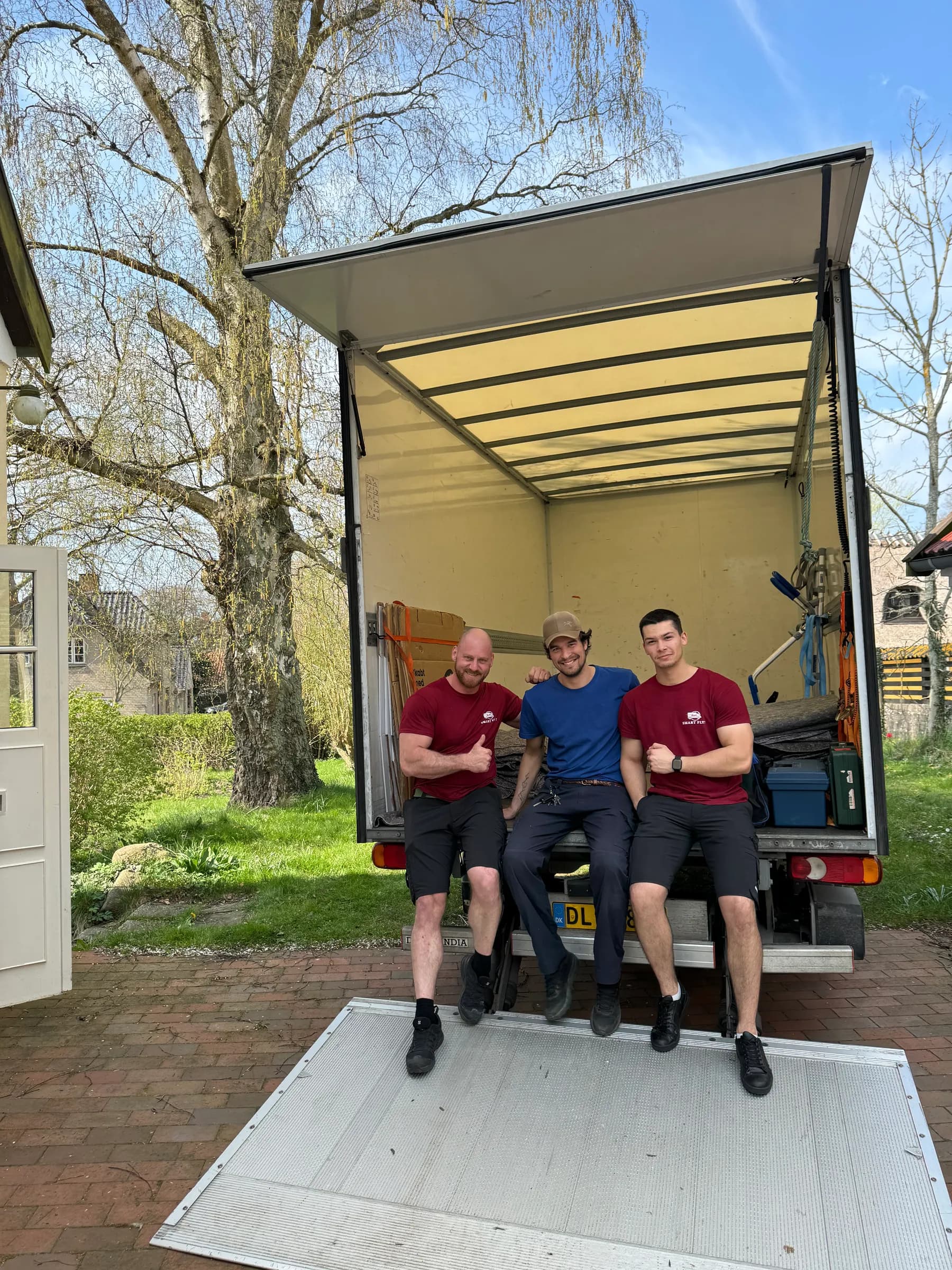 Three movers sitting on the loading ramp of the moving van