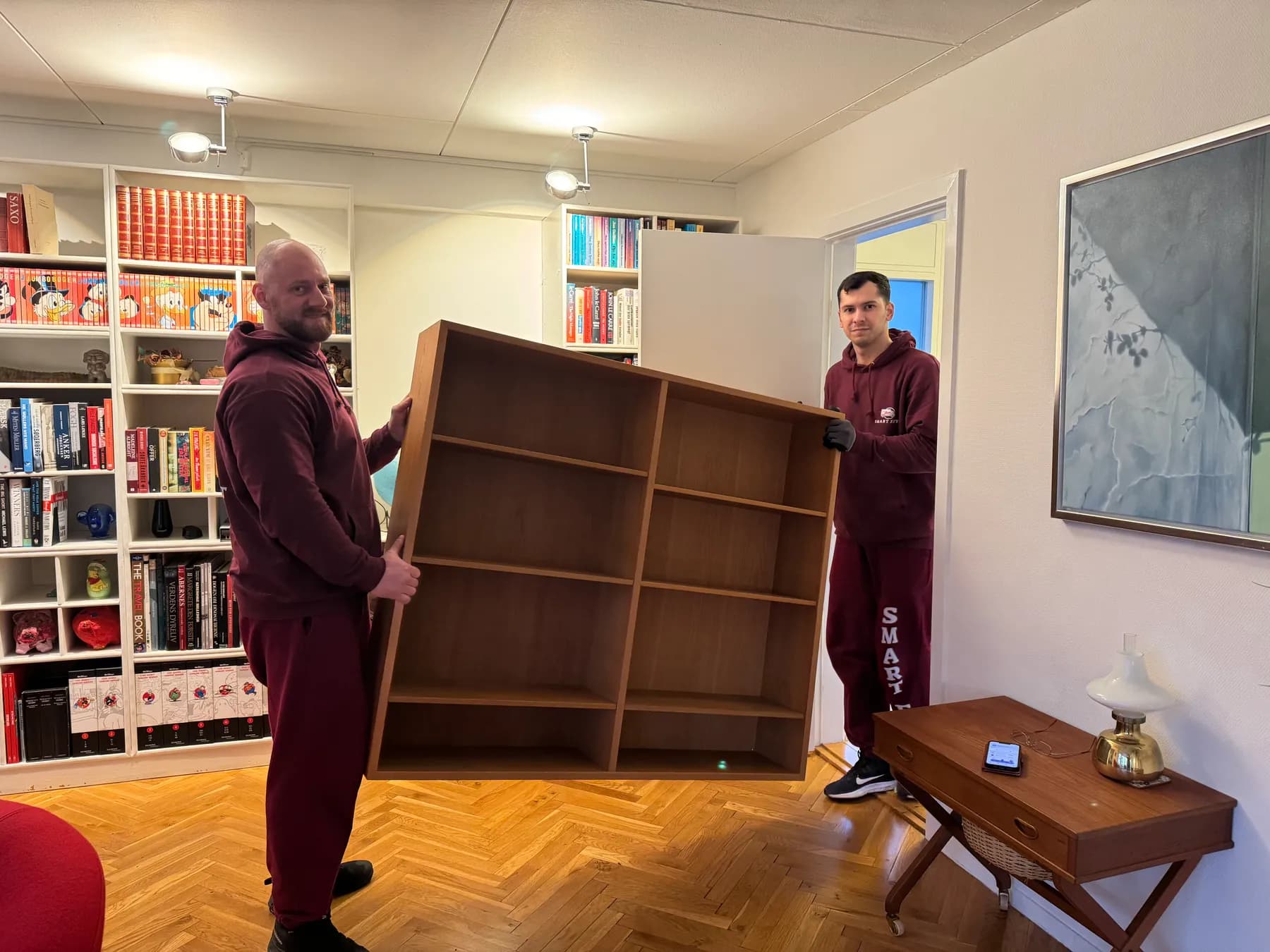 Two movers carrying a bookcase into a living room