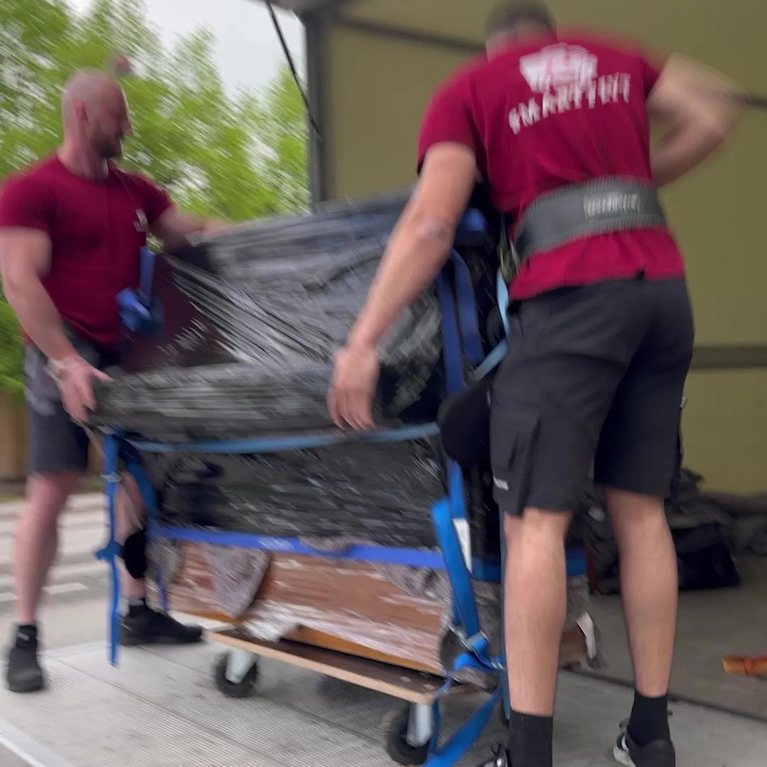 Two Smart Flyt movers wheel a sofa out on a trolley